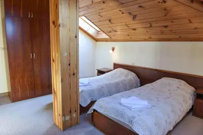 two beds in a room with wooden walls at Lovna sreshta in Bansko