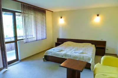 a bedroom with a bed and a table and a window at Lovna sreshta in Bansko