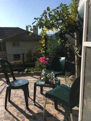 a patio with two chairs and a table with a flower on it at Нощувки Пловдив Тепето Plovdiv Hill in Plovdiv