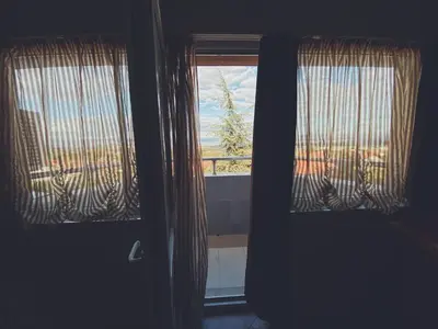 a room with two windows and a door with curtains at Hotel Fancy in Sofia
