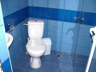 a bathroom with a white toilet and a blue tiled wall at МОТЕЛ СИТИ с БЕЗПЛАТЕН ПАРКИНГ in Plovdiv