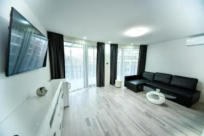 a living room with a black couch and some windows at Стаи за гости Десита in Blagoevgrad