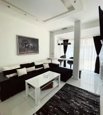a living room with a black couch and a table at Zero-Waste Studio Apartment in Central Sofia in Sofia