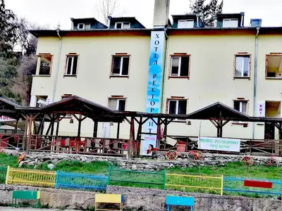 a large white building with black umbrellas in front of it at Семеен Хотел 