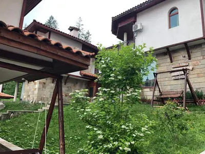 a yard with a building and a tree with white flowers at Pamporovo Villa in Pamporovo