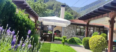 a building with an umbrella in a garden at СТАР МЕРАК in Ribarica