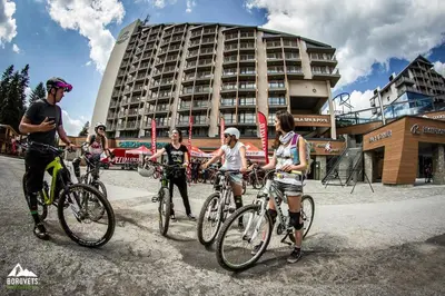 a group of people riding bikes in front of a building at VIVA Flora apartment 607A in Borovets