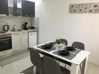 a kitchen with a white table with chairs and a counter top at Апартамент Рози in Sandanski