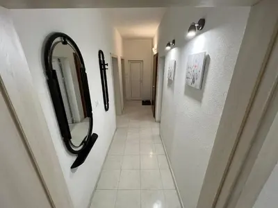a hallway with a mirror and a tile floor at Апартамент Рози in Sandanski