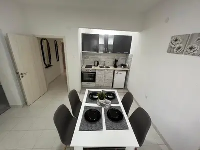 a small kitchen with a white table and chairs at Апартамент Рози in Sandanski