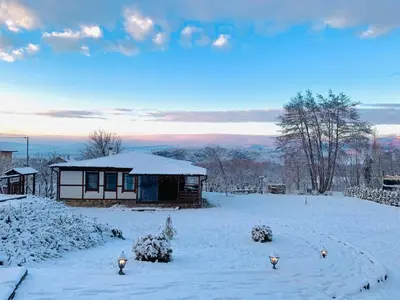 a snow covered yard with a cabin in the background at Villa Kashtata in Resilovo