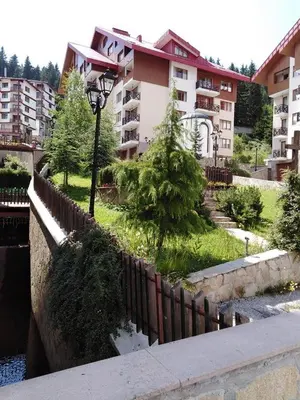 a building with a fence next to a body of water at Ски апартамент, студио Хрис, Лъки Пампорово in Pamporovo