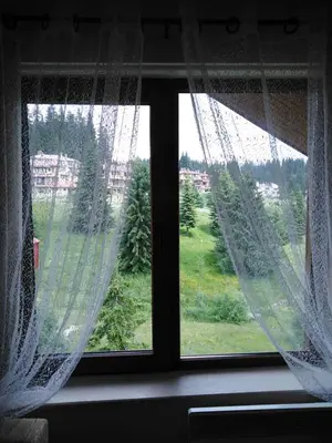 a window with curtains and a view of a field at Ски апартамент, студио Хрис, Лъки Пампорово in Pamporovo