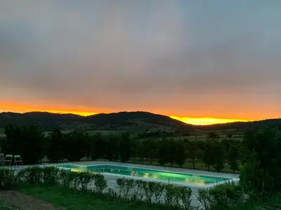 a pool with a sunset in the background at Планински кът in Dorkovo