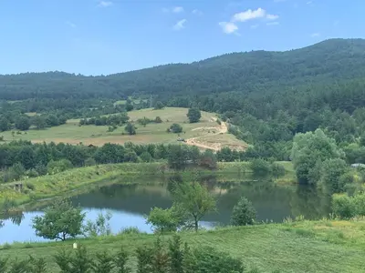 a view of a lake in the middle of a field at Планински кът in Dorkovo