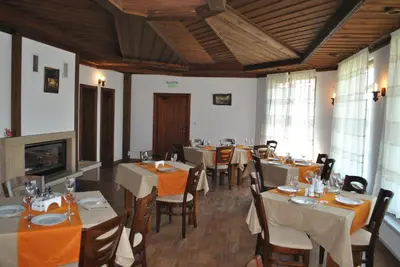 a dining room with tables and chairs and a fireplace at Планински кът in Dorkovo