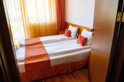 a small bedroom with a bed with orange pillows at Two bedroom apartments in Murphys Lodge in Bansko