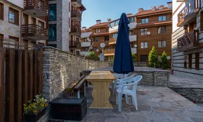 a patio with a table and an umbrella and chairs at Two bedroom apartments in Murphys Lodge in Bansko
