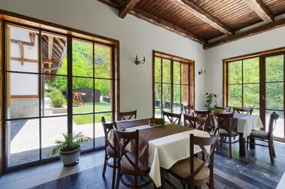 a dining room with tables and chairs and large windows at Hotel Apostolite in Sandanski