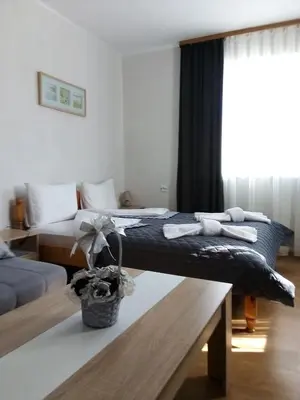 a bedroom with two beds and a table and a window at Holiday guest house KEMO in Sapareva Banya