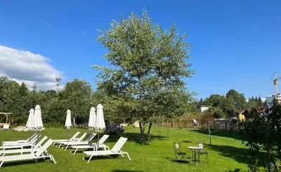 a group of white lounge chairs and tables in a field at Predela LUX Aparthotel in Bansko