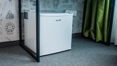 a white refrigerator sitting in a room next to a curtain at A&M Hotel with free parking in Plovdiv