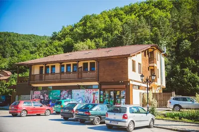 a building with cars parked in a parking lot at Стаи за гост Хит Хаус и СПА in Bratsigovo