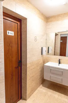 a bathroom with a sink and a wooden door at Стаи за гост Хит Хаус и СПА in Bratsigovo
