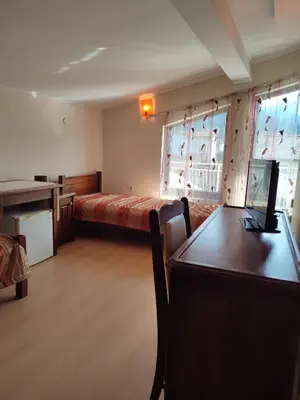 a room with a bed and a desk with a laptop at Къща за гости M-Stone in Bansko