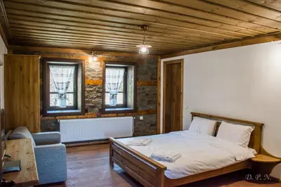 a bedroom with a bed and a couch and windows at Пачаловата къща in Kovachevitsa