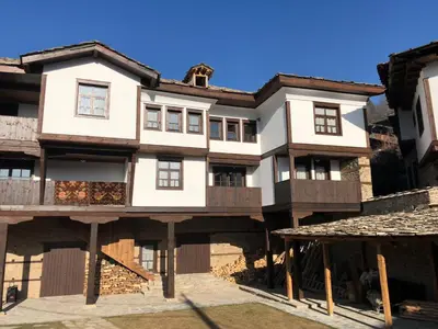 a large white house with wooden balconies on a building at Пачаловата къща in Kovachevitsa