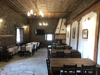a dining room with tables and chairs and a flat screen tv at Пачаловата къща in Kovachevitsa