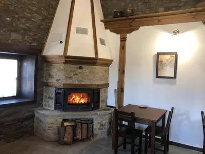 a living room with a stone fireplace and a table at Пачаловата къща in Kovachevitsa