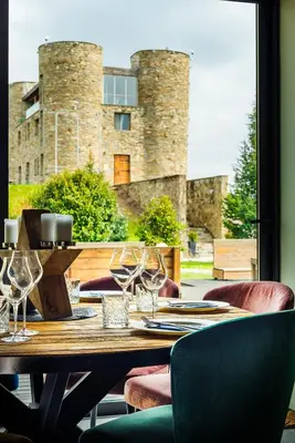 a wooden table with wine glasses and a building in the background at Chateau Copsa Complex in Moskovets