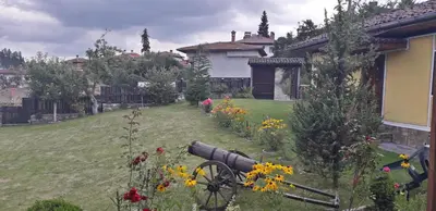 a garden with flowers and a cannon in the yard at Mechta Guest House in Koprivshtitsa