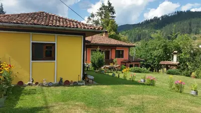 a yellow house in a yard with a garden at Mechta Guest House in Koprivshtitsa