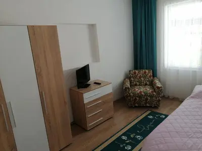 a bedroom with a dresser with a television and a chair at Къща за гости Жани in Zmeitsa