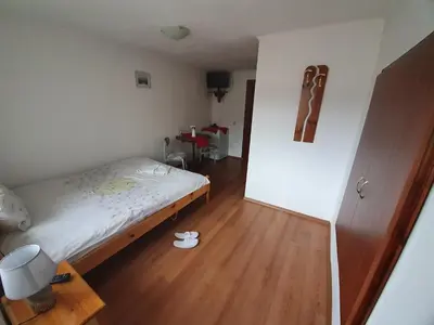 a small bedroom with a bed and a wooden floor at Тодор Прегьов in Bansko