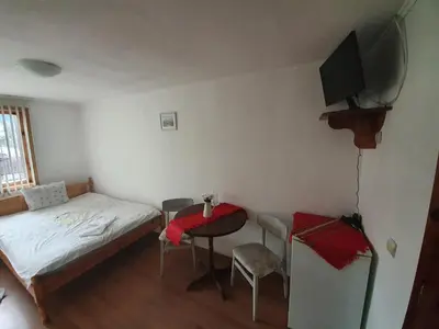 a small bedroom with a bed and a table and chairs at Тодор Прегьов in Bansko