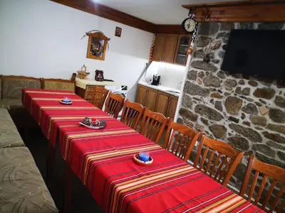a dining room with two tables and a stone wall at стаи за гости Диневи in Kalofer