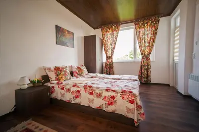 a bedroom with a bed and a window with curtains at Стаи за гости - Къща ТОНЧЕВИ in Kalofer