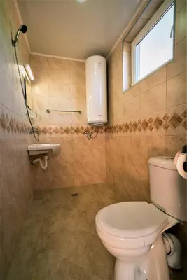 a bathroom with a toilet and a window and a sink at Стаи за гости - Къща ТОНЧЕВИ in Kalofer