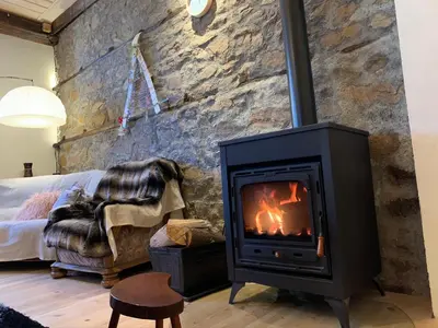 a fireplace in a living room with a stone wall at EskiZ - Our stone home in Chepelare