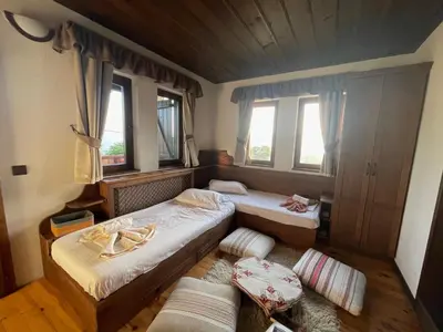 two beds in a room with two windows at Къща за гости Родопски изгрев in Leshten