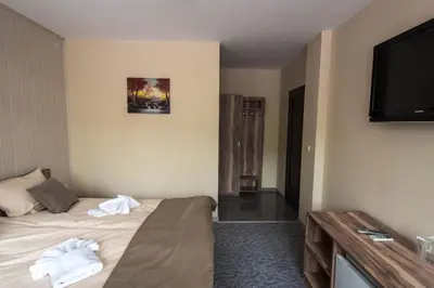 a hotel room with a bed and a flat screen tv at Etobicoke -Стаи за гости in Etropole