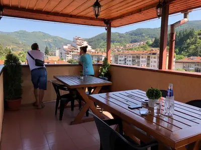 two women standing on a balcony with tables and chairs at Стаи за Гости Тони и Крис in Devin