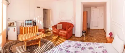 a living room with an orange chair and a television at Sofia Apartment in House 8 boulevard Hristo Botev in Sofia