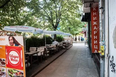 an empty street with tables and chairs on a sidewalk at Sofia Apartment in House 8 boulevard Hristo Botev in Sofia