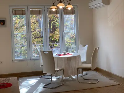 a dining room with a table and chairs and windows at ViITOSHKA Apartment in Sofia