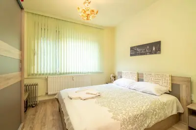a bedroom with a large bed with a chandelier at Апартаменти Уют in Plovdiv
